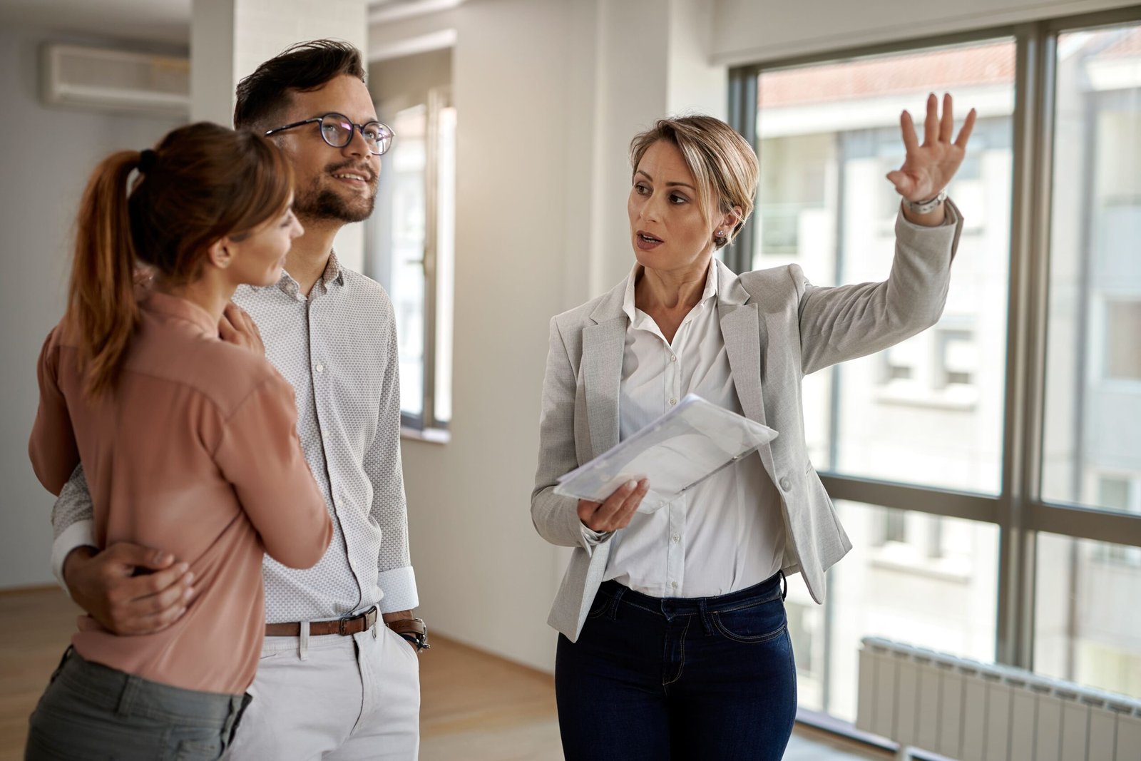 young couple communicating with real estate agent while buying their new home focus is agent (1)