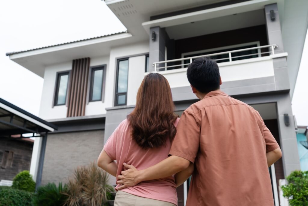 young couple standing outside looking their house(1)